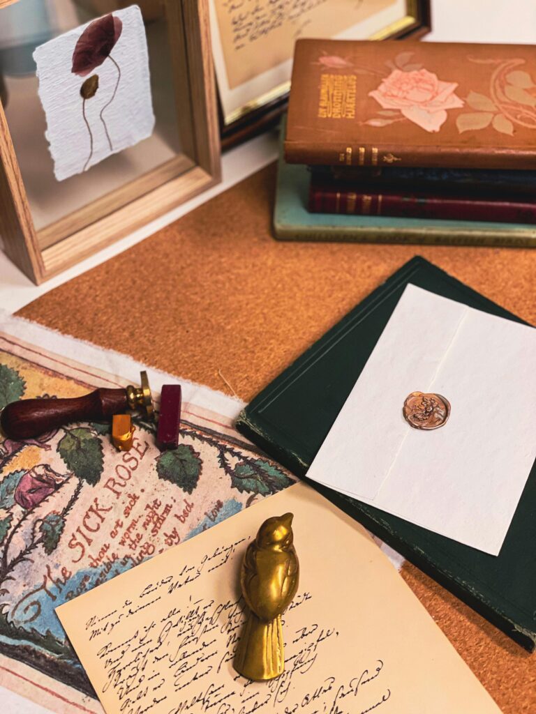 Artistic flatlay of vintage stationery, books, and a sealed envelope with a wax seal.