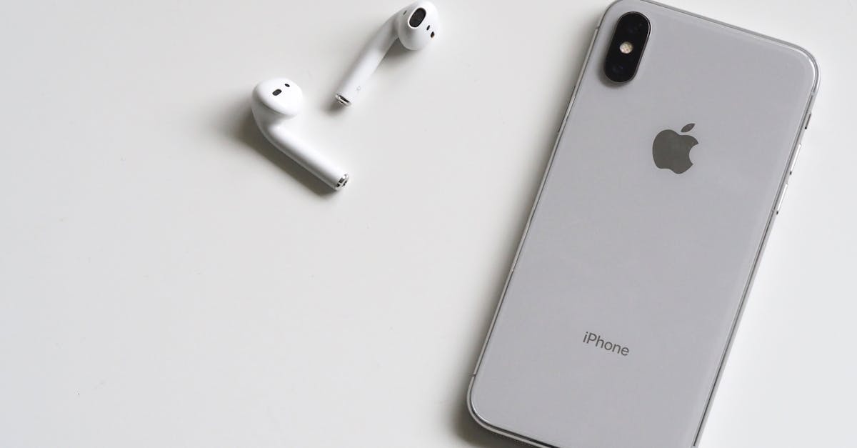 Close-up of a silver iPhone and wireless AirPods on a sleek white background.